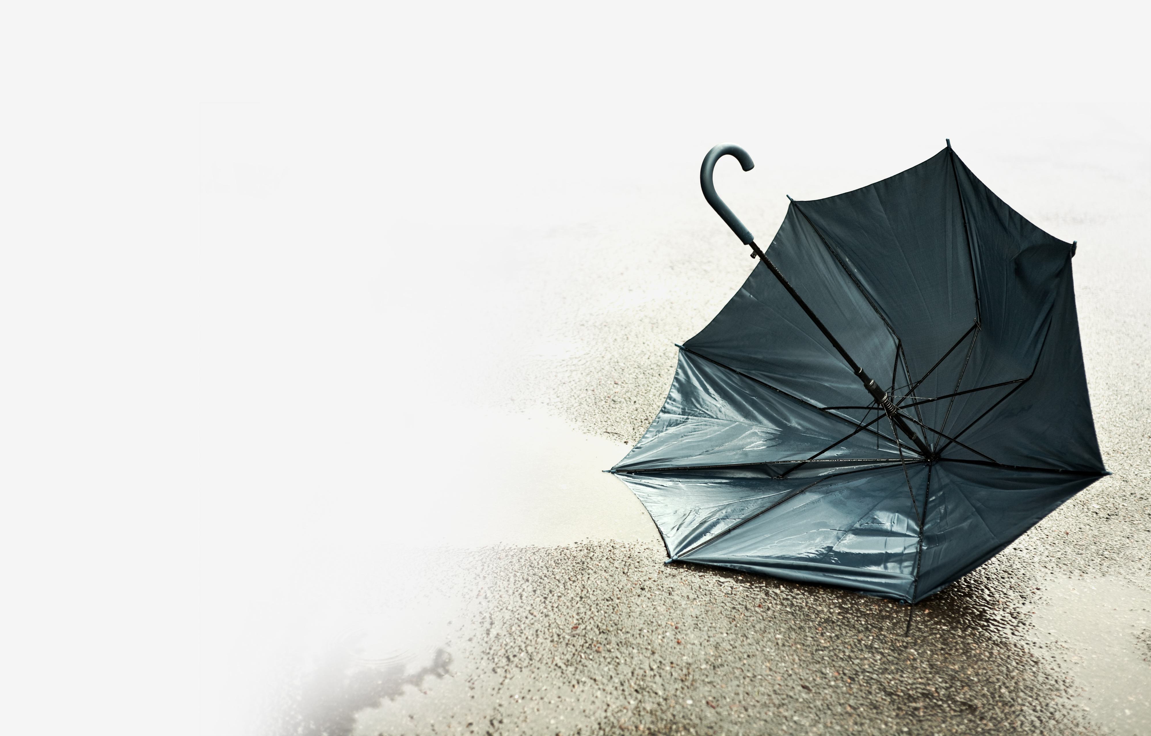 Broken umbrella blown over onto the sand on a beach.