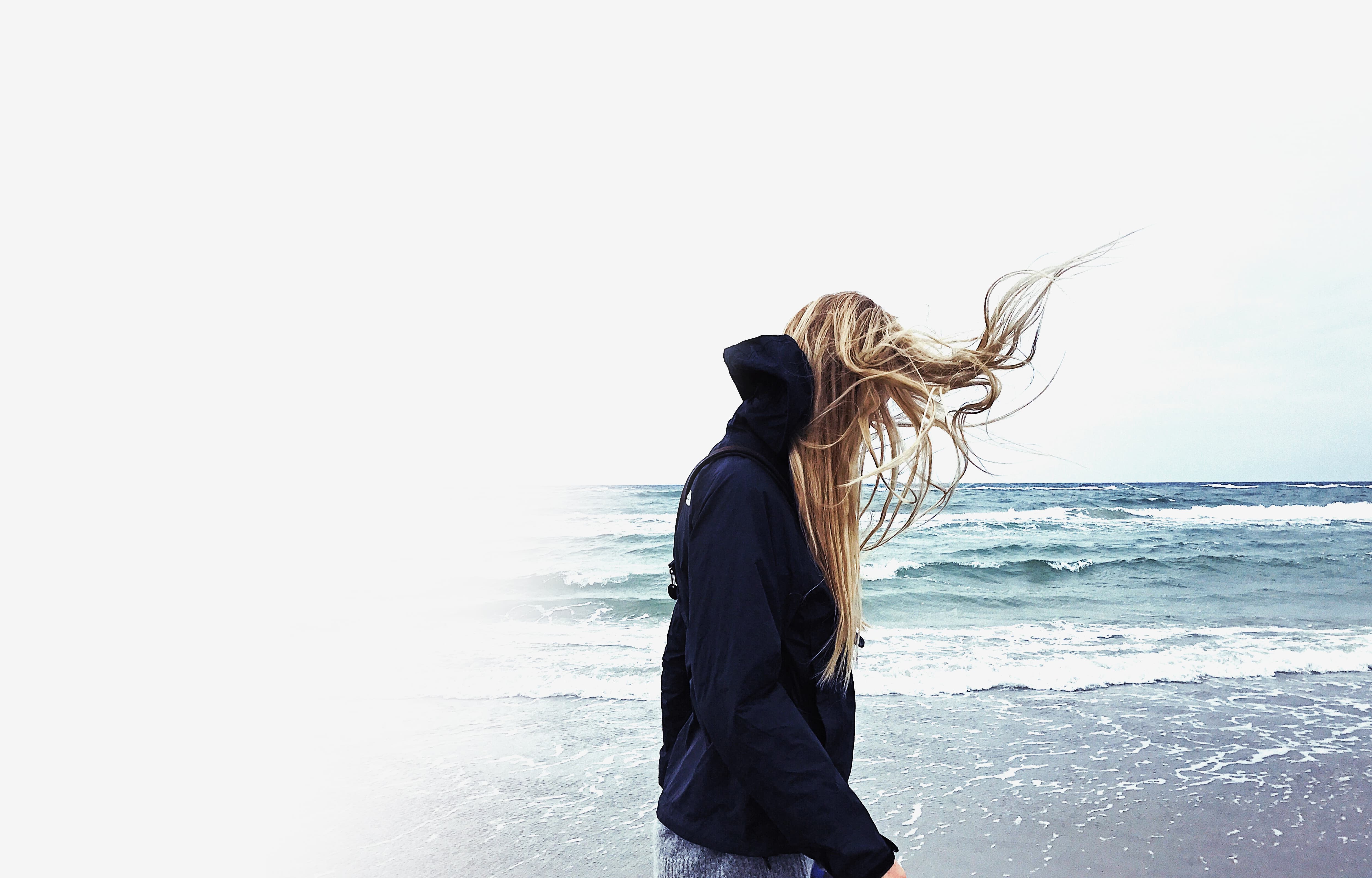 Woman walking along the seafront with wind blowing into her hair.